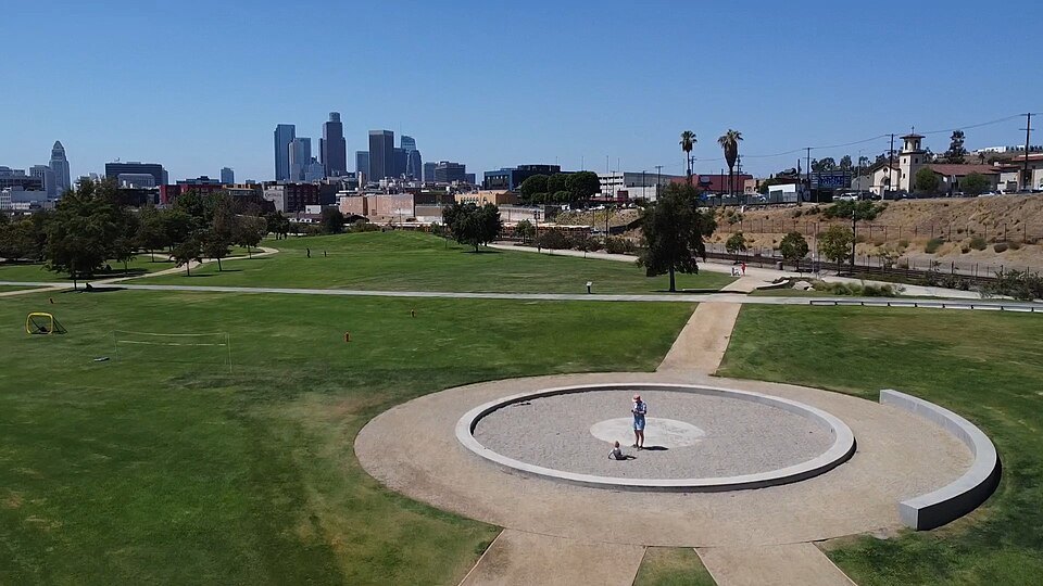 Lawn and paths at Los Angeles State Historic Park with downtown in the distance