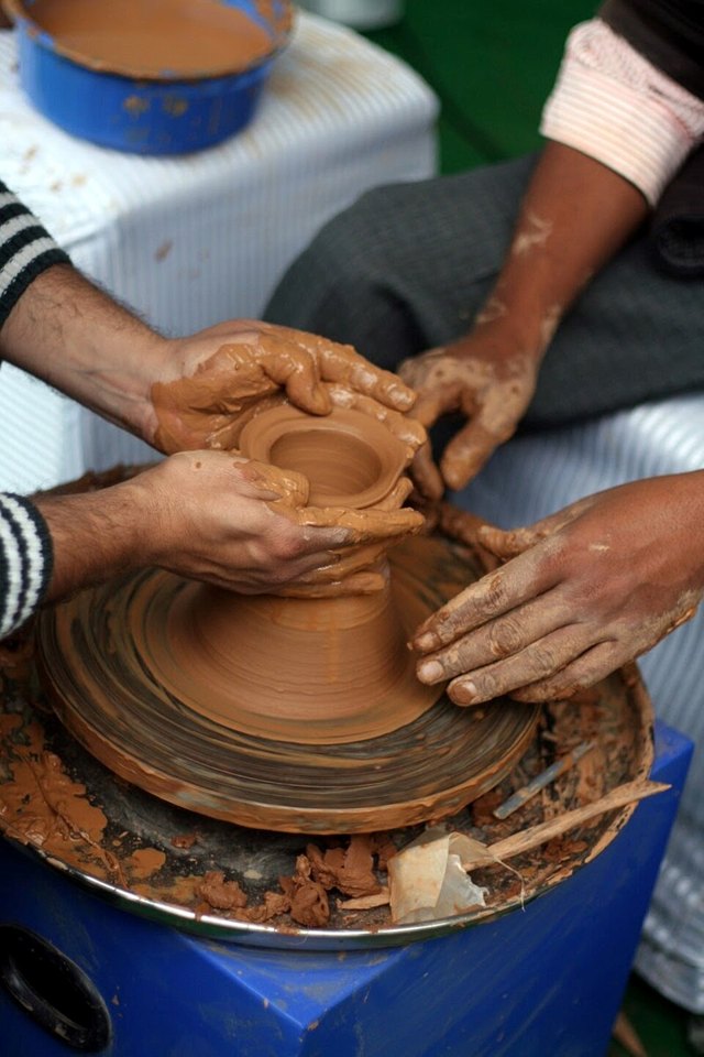 Hands shaping wet clay on a pottery wheel